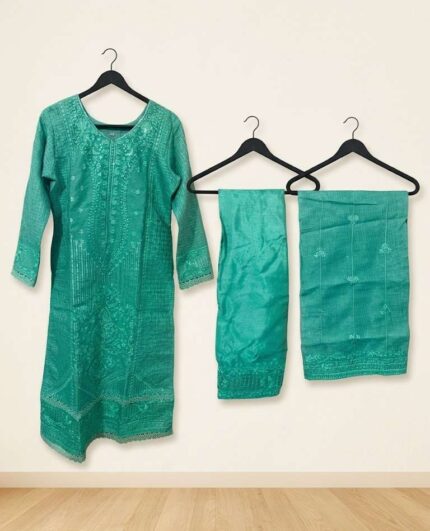A woman modeling a premium sea green chomok silk kota embroidered stitched three-piece dress, showcasing detailed self-embroidery and sequin work on the neckline and hem, paired with a matching embroidered kota dupatta and soft silk trousers.