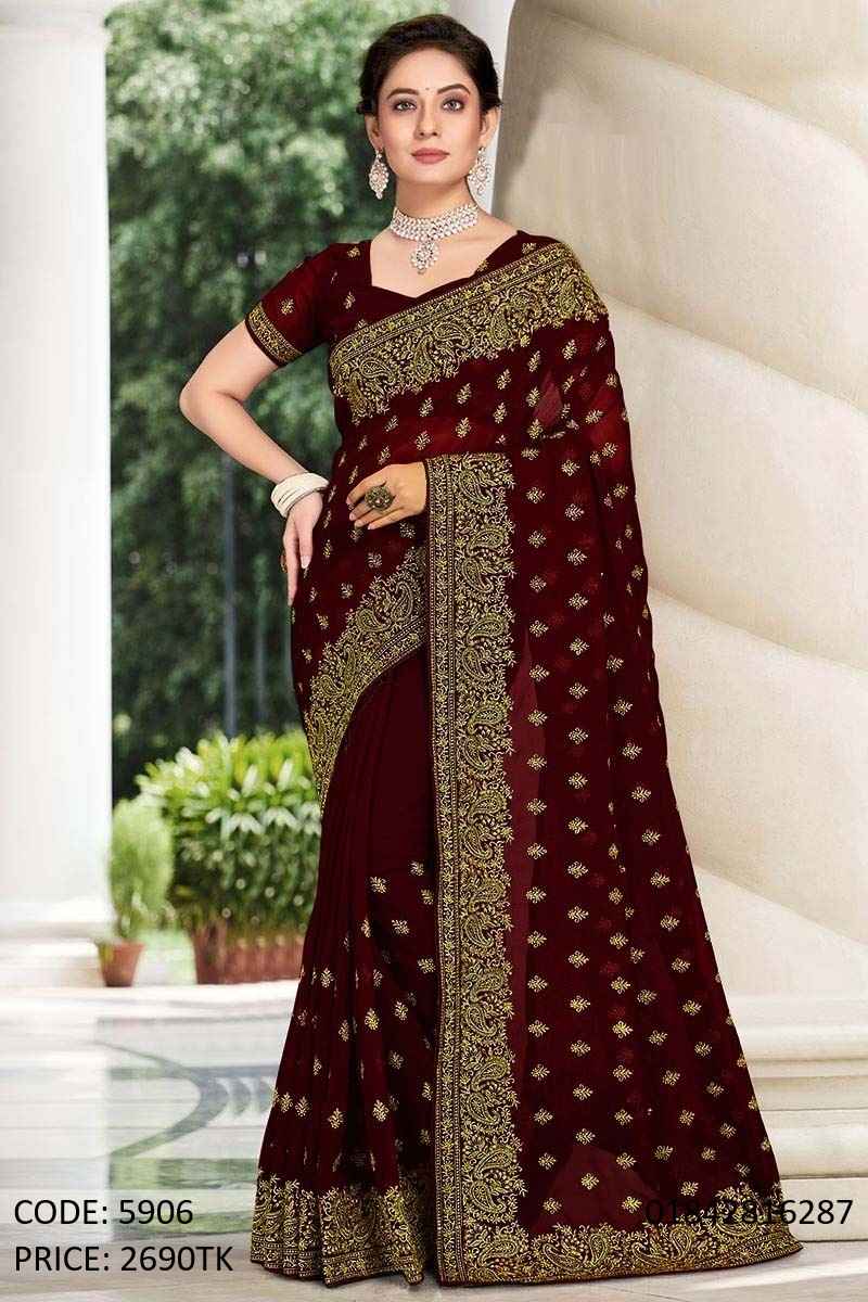 Maroon Soft Georgette Embroidery and Sequence Work Saree A woman modeling a beautiful maroon soft georgette saree featuring intricate golden embroidery and sequence work with a matching blouse.