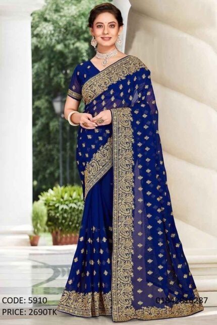 A full-length photo from image_0.png of a woman wearing a rich royal blue soft georgette saree, adorned with intricate gold paisley embroidery and shimmering gold sequins, styled for a party. She is standing outdoors with a graceful pose.